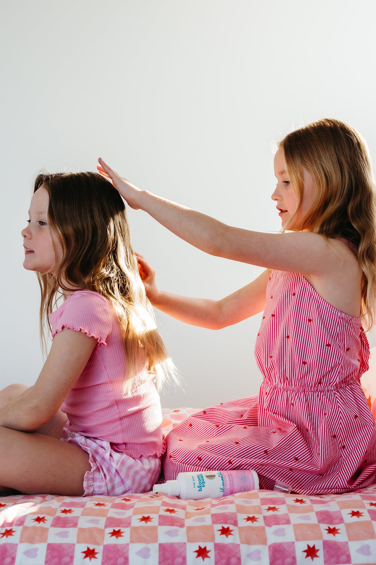Two girls brushing each others hair with detangler spray