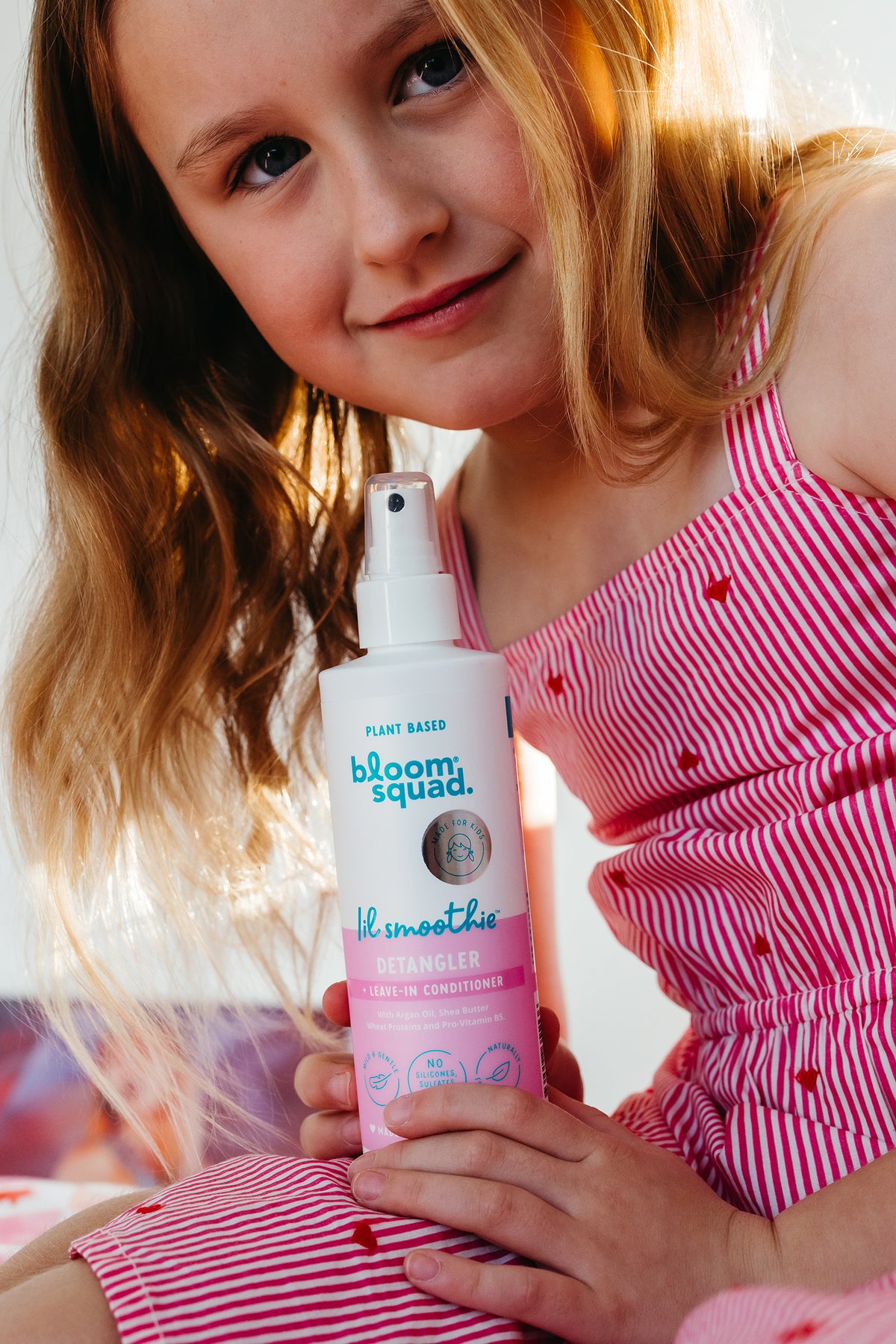 Little girl with pink dress holding detangler